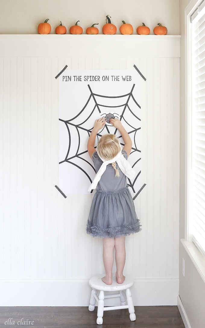A little girl playing a Halloween kids game called pin the spider on the web. 