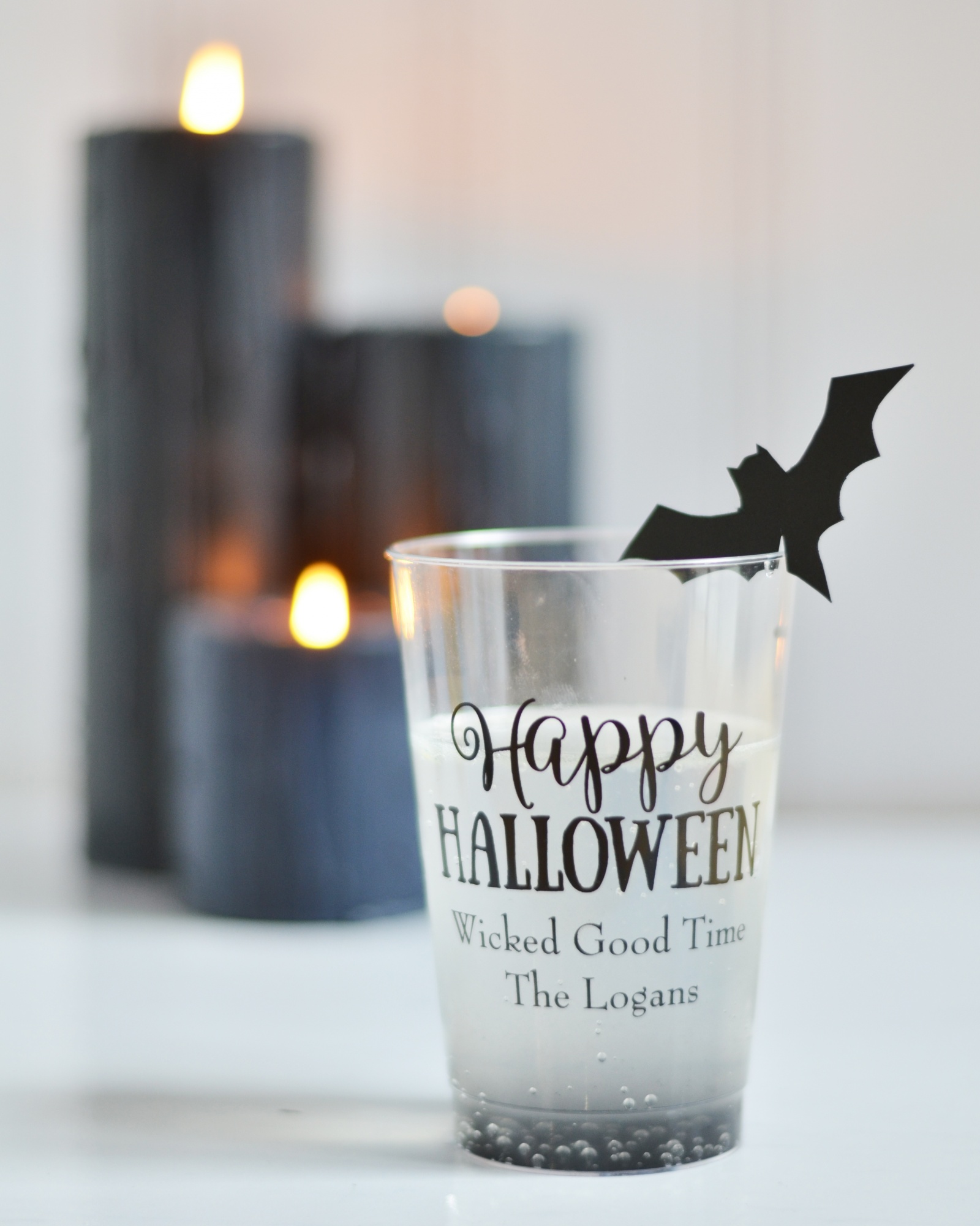 A black charcoal Halloween cocktail in a personalized Halloween cup with a bat